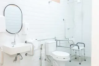 Banheiro adaptado com barras de apoio junto ao vaso sanitário e bancada