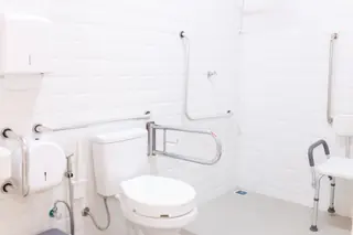 Área de banho com barras de apoio e cadeira de banho