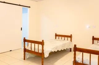 Dormitório da Casa Hiro com camas de madeira e quadros na parede