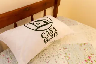 Travesseiro com a marca da Casa Hiro sobre uma cama preparada