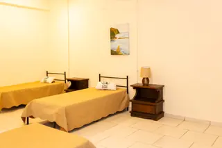 Quarto da Casa Hiro com camas preparadas e mesa de cabeceira