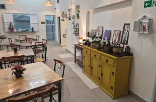 Ambiente de refeições da Casa Hiro com mesas de madeira e móvel amarelo