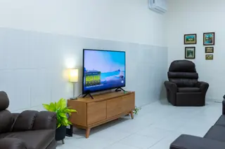 Sala de estar da Casa Hiro com sofá, poltrona e televisão